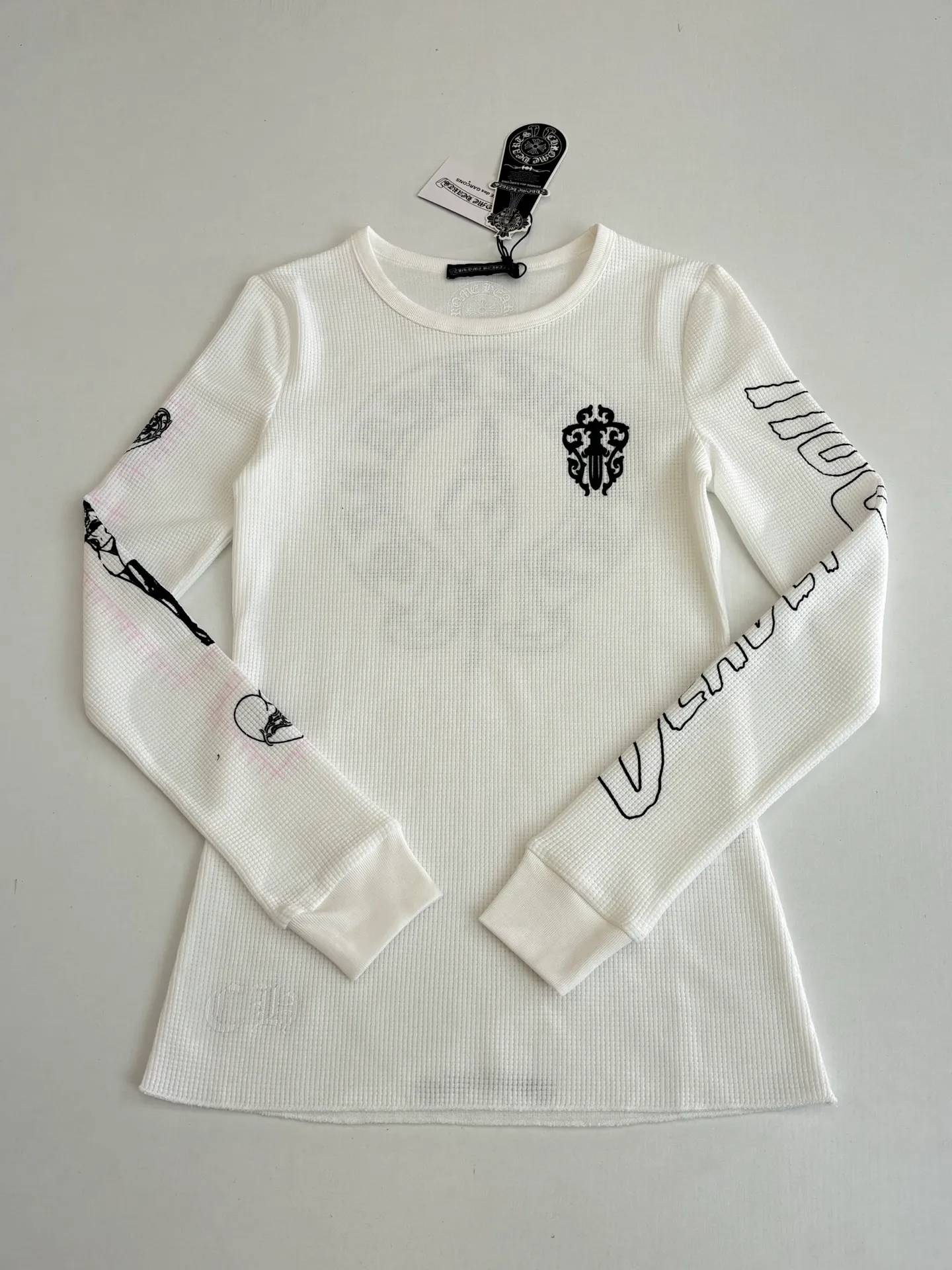P266 (Slim fit women's style) Chrome Heart*/Ch character Sanskrit printed waffle long-sleeved T-shirt is woven with 32-count blended yarn. The fabric composition is 30% cotton and 70% polyester, with a weight of 220 grams. It ensures a stiff fit while taking into account the skin-friendly properties of cotton fiber and the anti-wrinkle and easy-care properties of polyester. The body of the garment adopts a waffle knitted structure, forming a three-dimensional texture and good breathability and moisture removal. Screen printing technology is used in the printing process to accurately present the brand's iconic Gothic fonts, totem patterns and character patterns on the front, back and sleeves of the garment. The printing layer has strong adhesion and the pattern outline is clear. Size: S/M/L